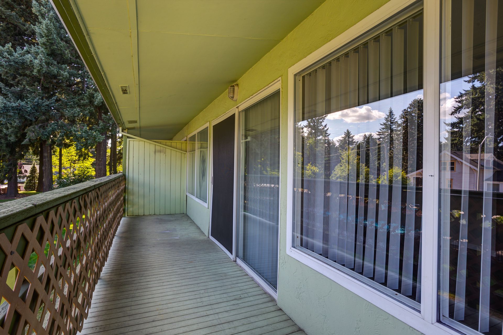 A balcony with sliding glass doors and blinds on the windows