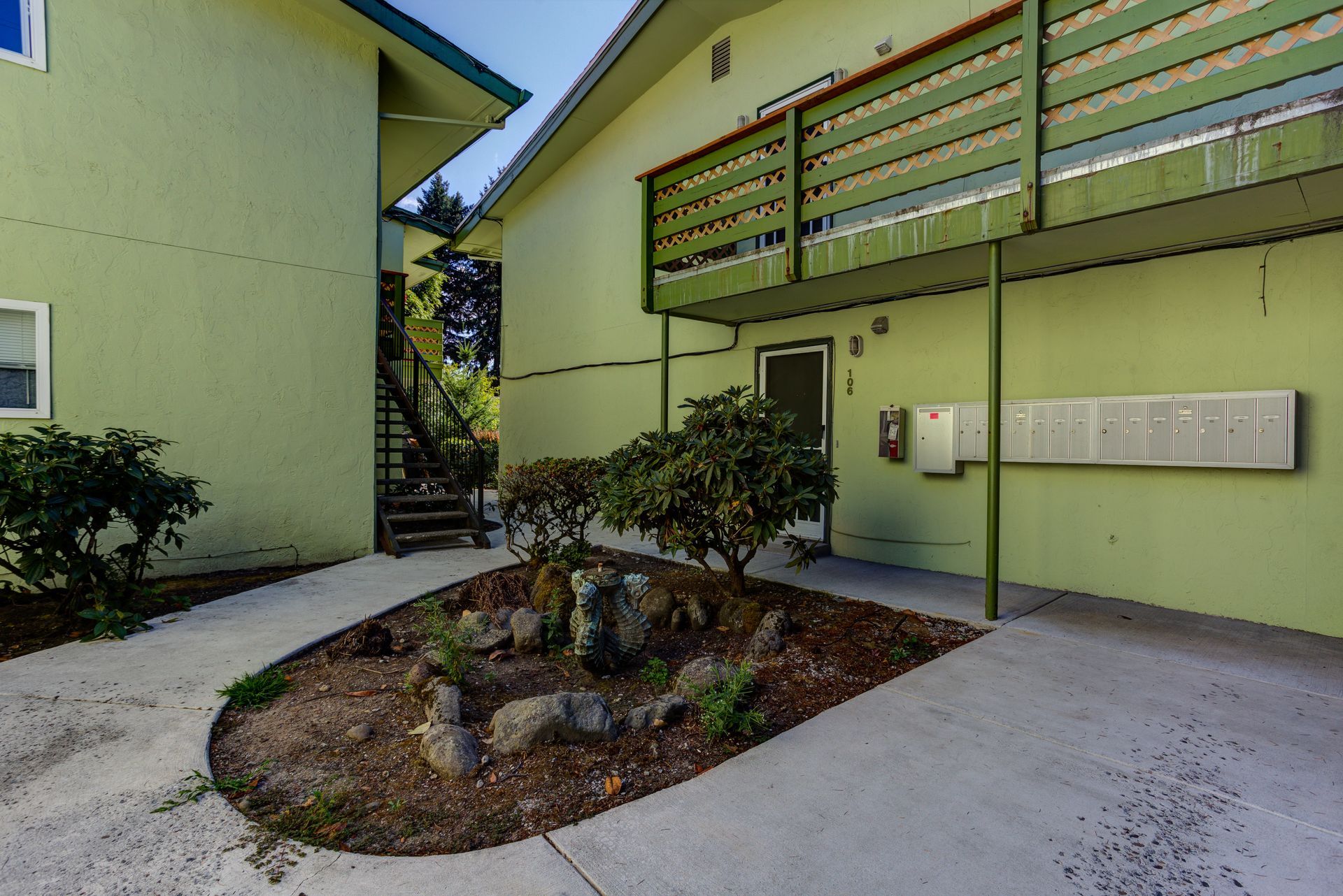 A green building with stairs leading up to the second floor
