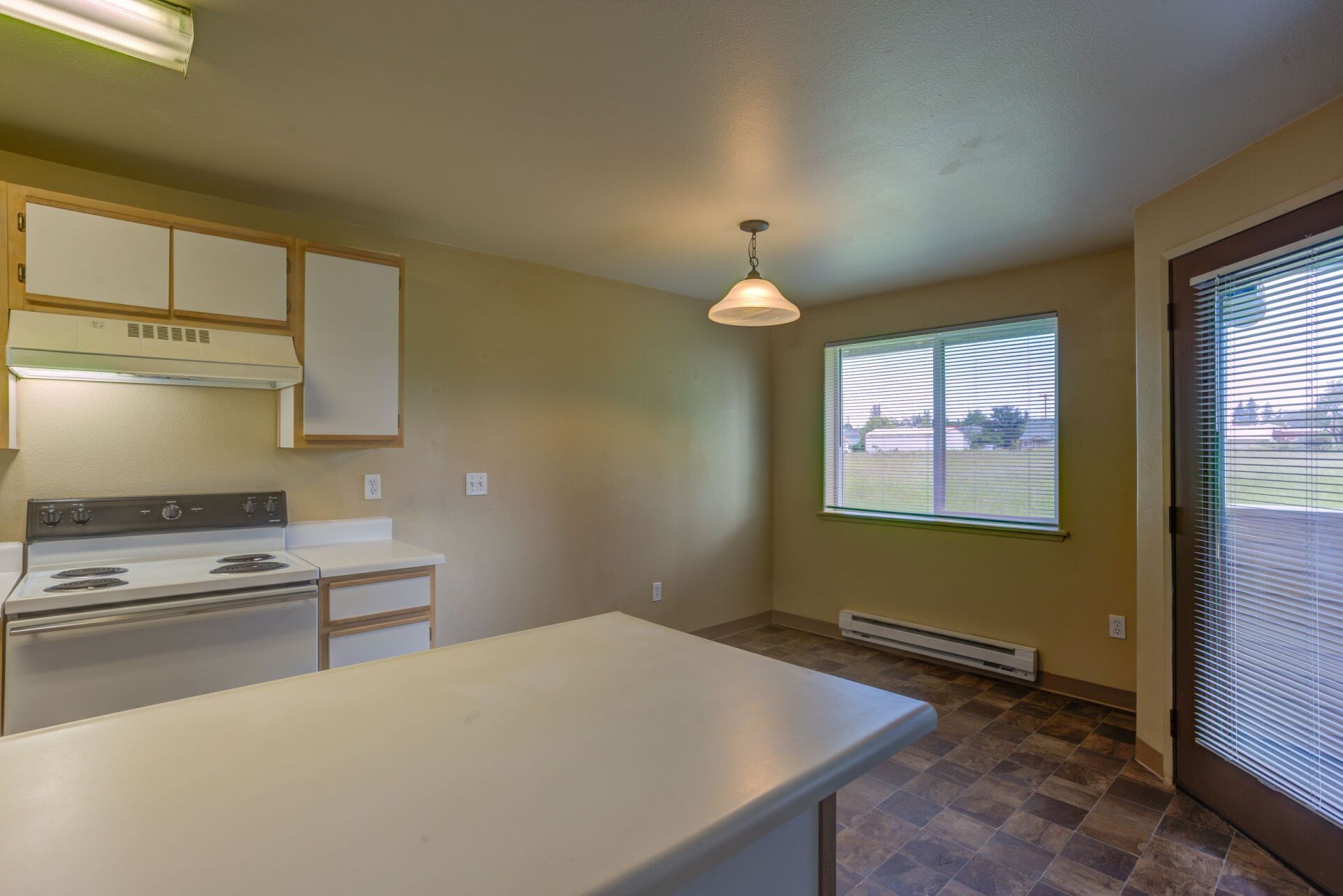 An empty kitchen with a stove , dishwasher , and a large island.