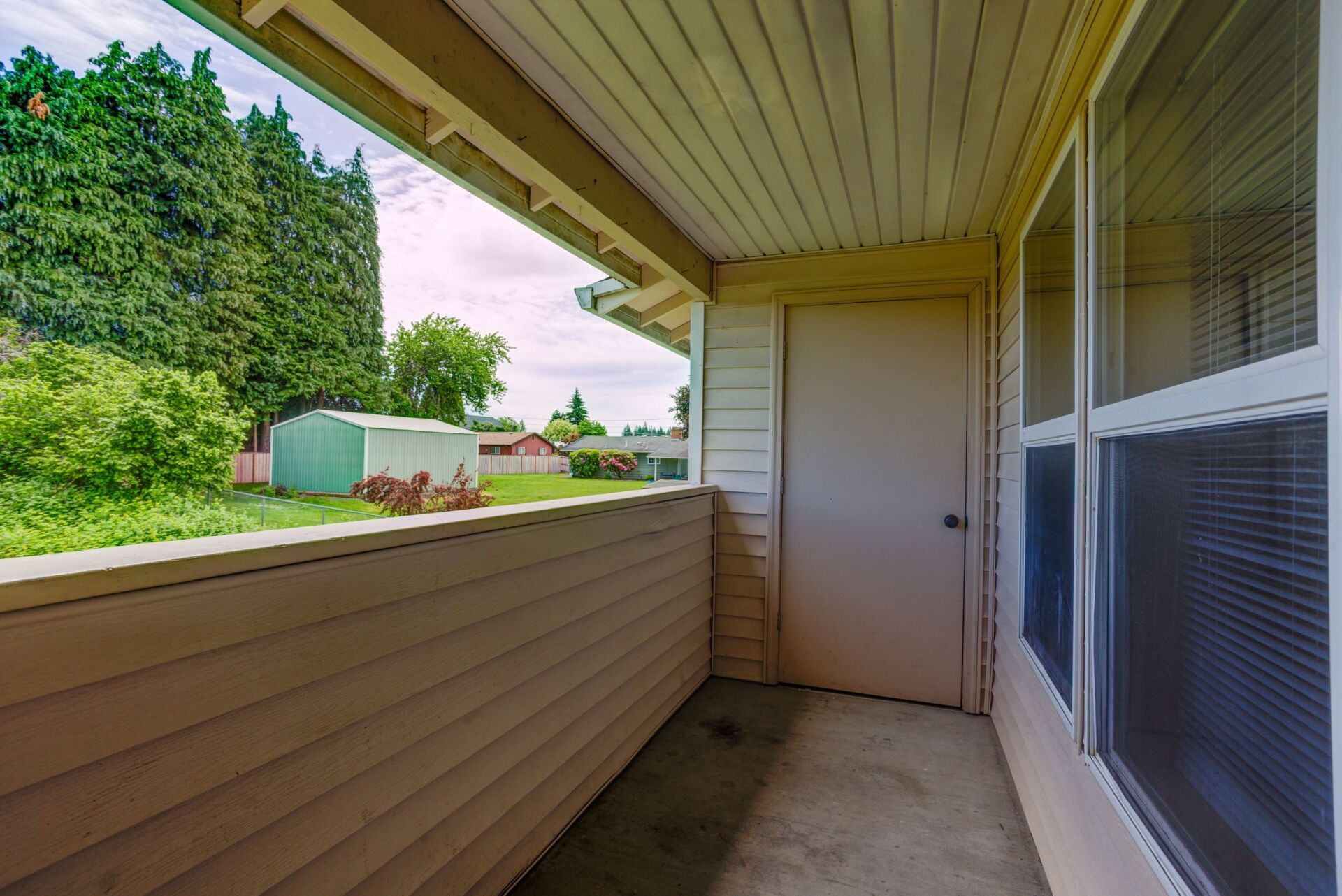 A balcony with a view of a yard and trees