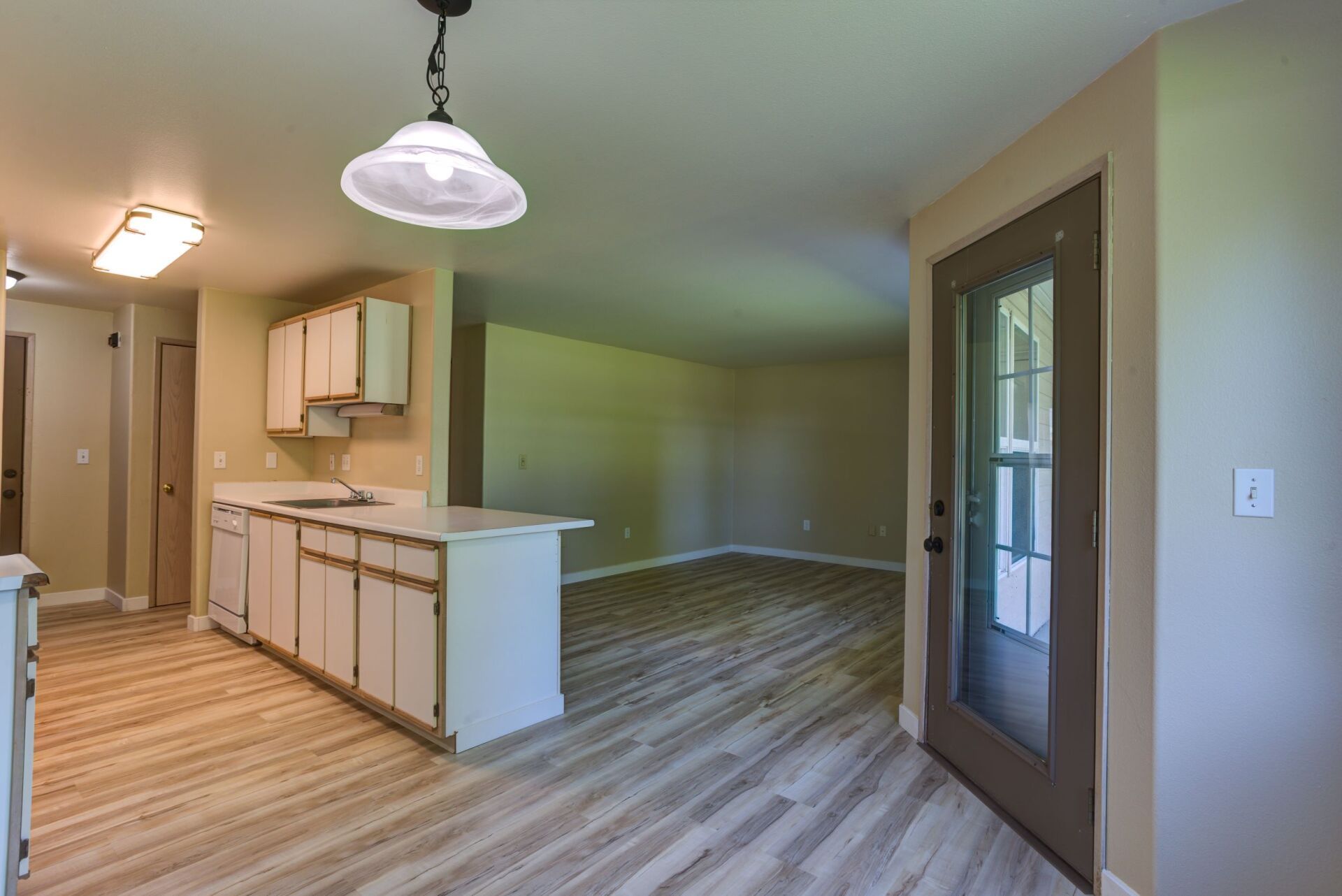 An empty house with a kitchen , living room , and dining room.
