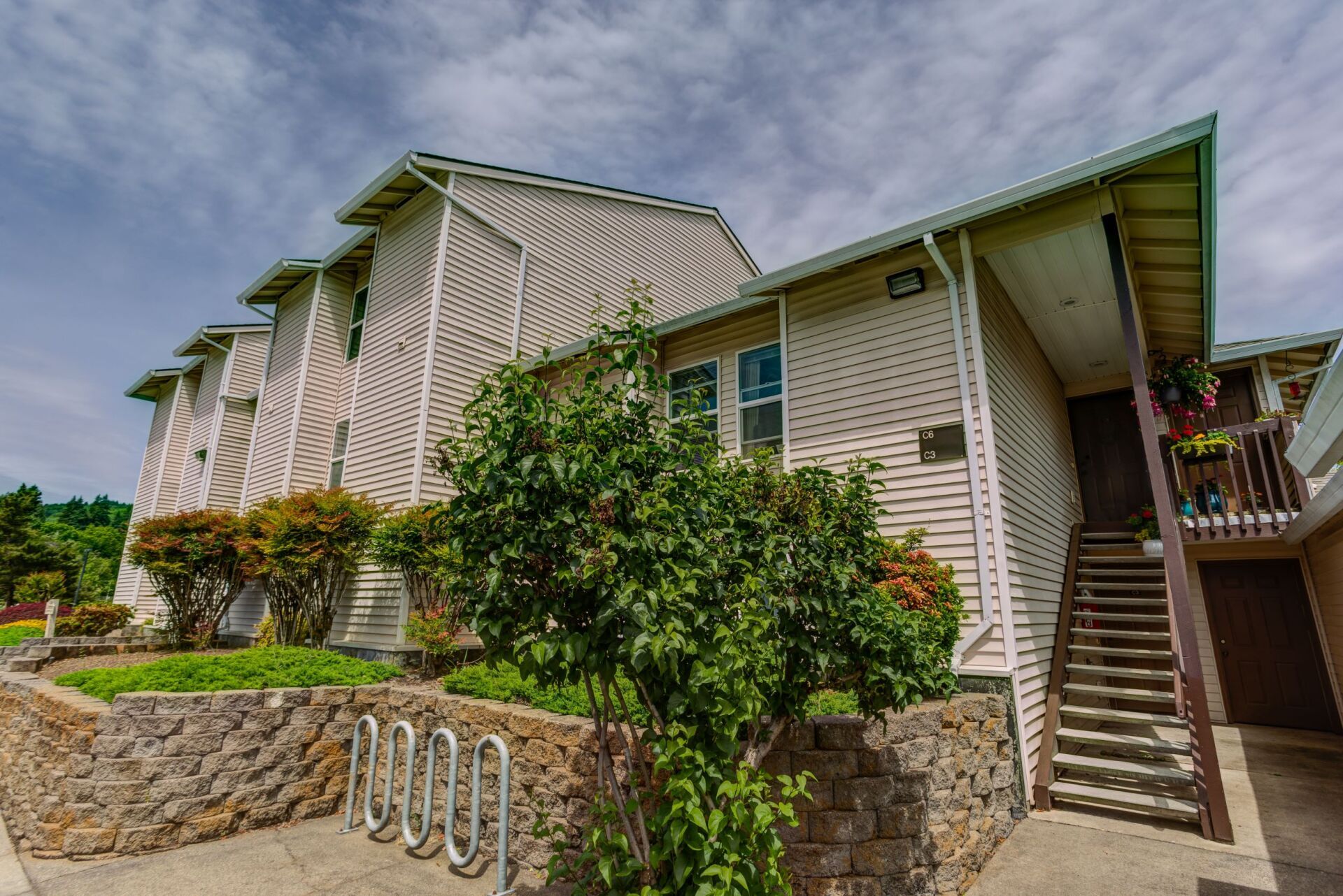 A large apartment building with stairs and a bike rack in front of it.