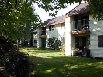 A row of apartment buildings with balconies surrounded by trees