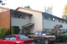 A red car is parked in front of a building with a truck parked in front of it.