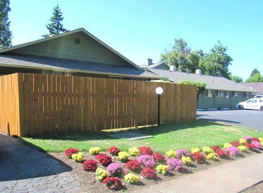 A house with a wooden fence and flowers in front of it