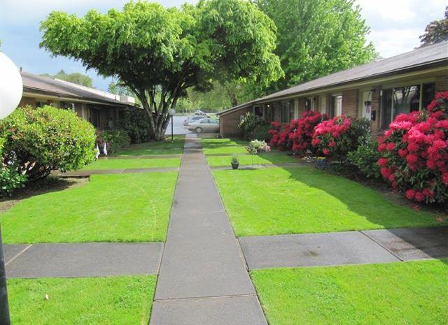 A walkway leading to a building with a lot of grass and flowers