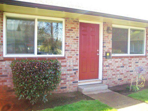 A brick house with a red door and white windows