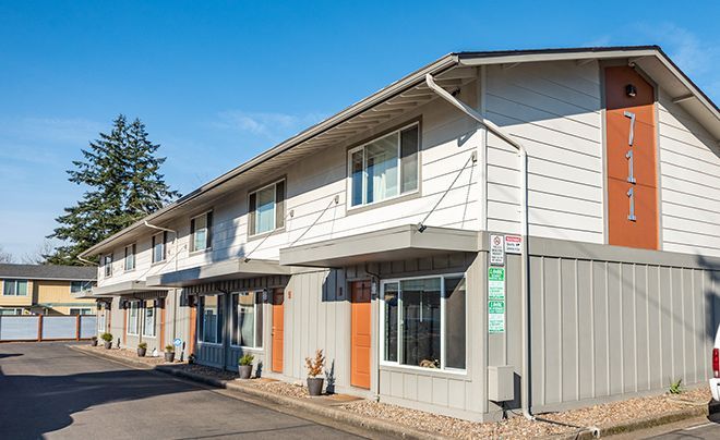 A living room with a coffee table , chair , dresser and stairs.