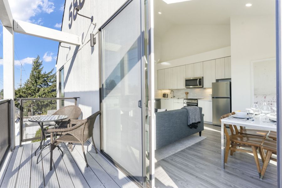 A balcony with a table and chairs next to a kitchen.