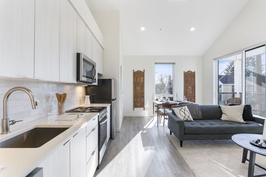 A kitchen with a sink , stove , refrigerator , microwave and a couch.