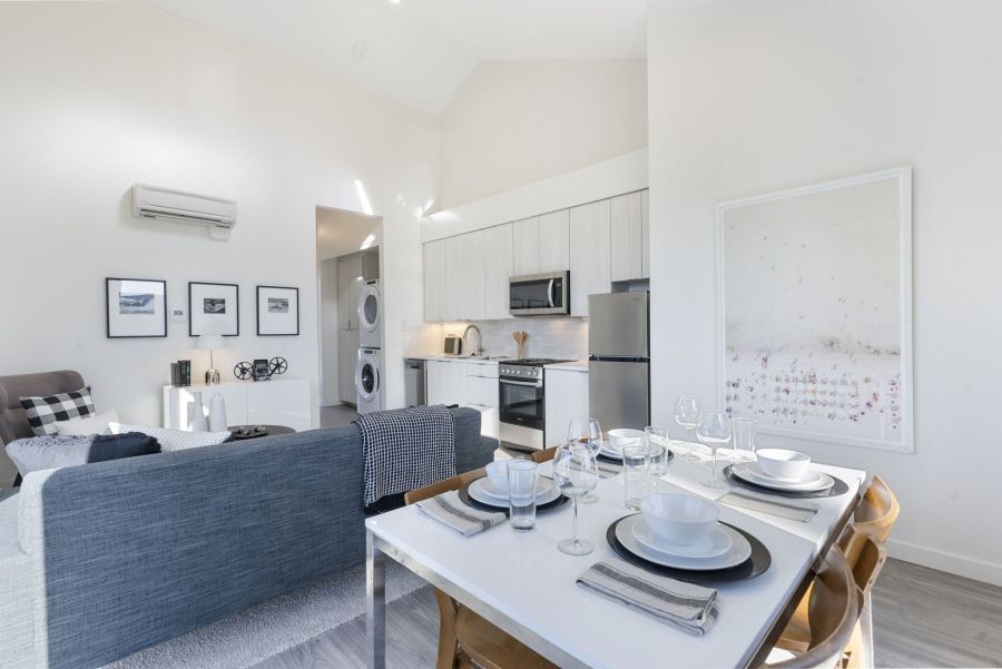 A living room with a dining table and chairs and a kitchen.