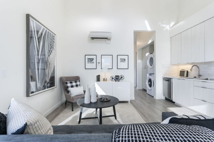 A living room with a couch , chair , coffee table and kitchen.