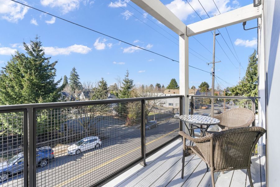A balcony with a table and chairs overlooking a city street.