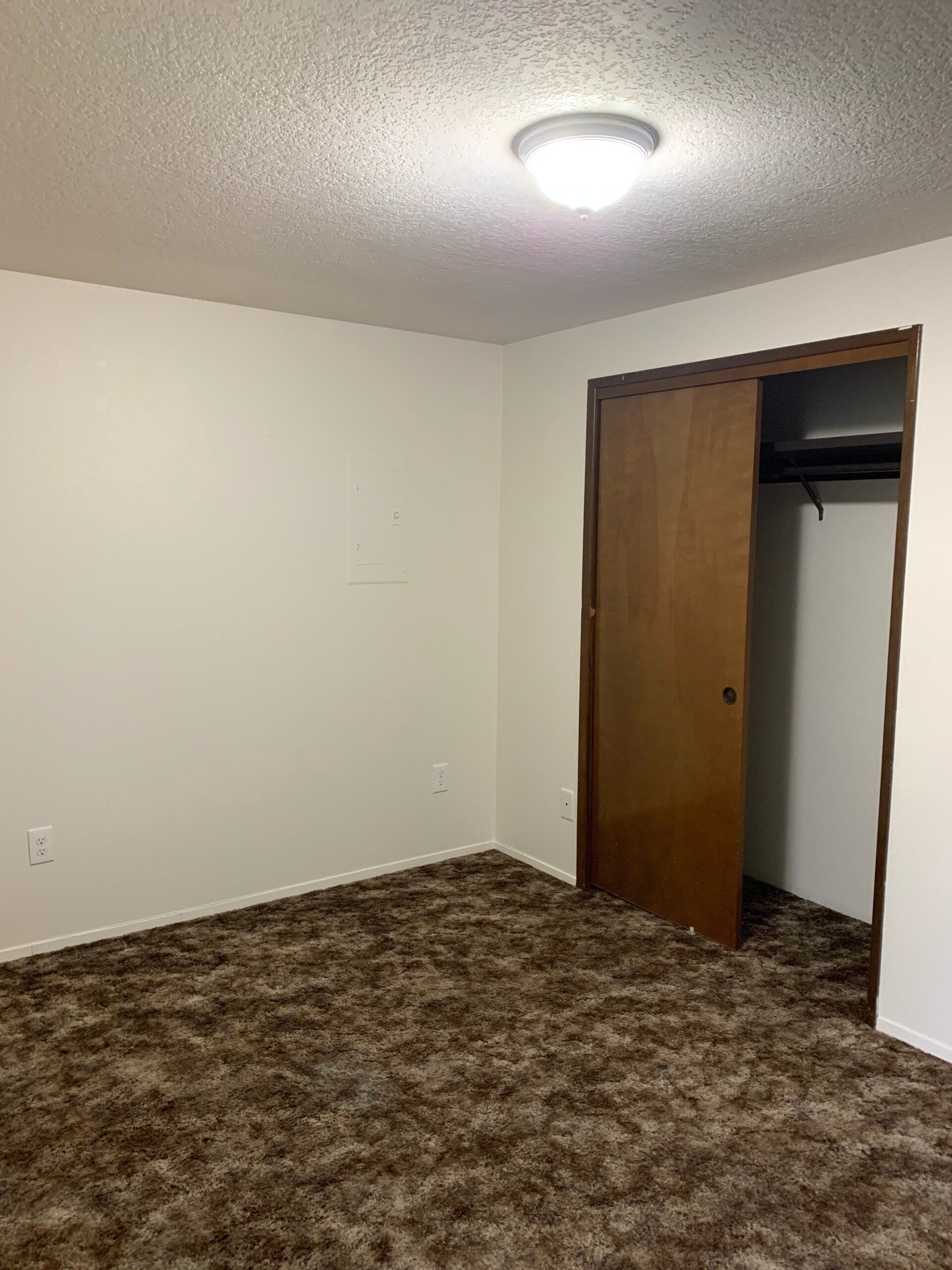 An empty bedroom with a closet and a light on the ceiling.
