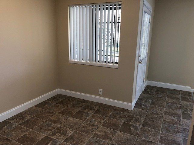 An empty room with a window and tile floor.