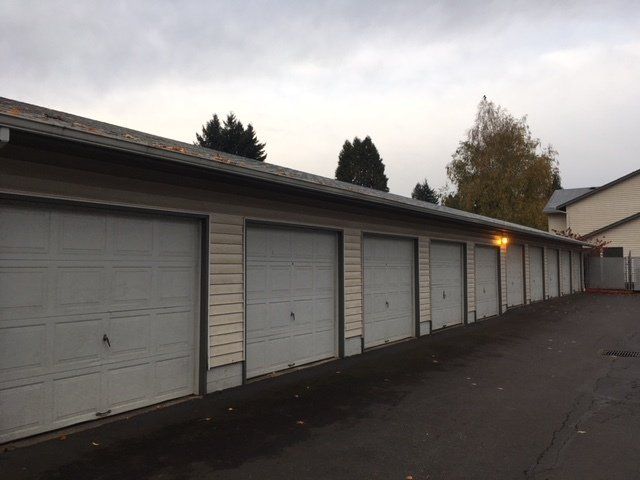 A row of garage doors on a building with trees in the background