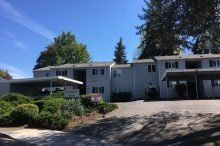 A large white house with a lot of windows and trees in front of it.