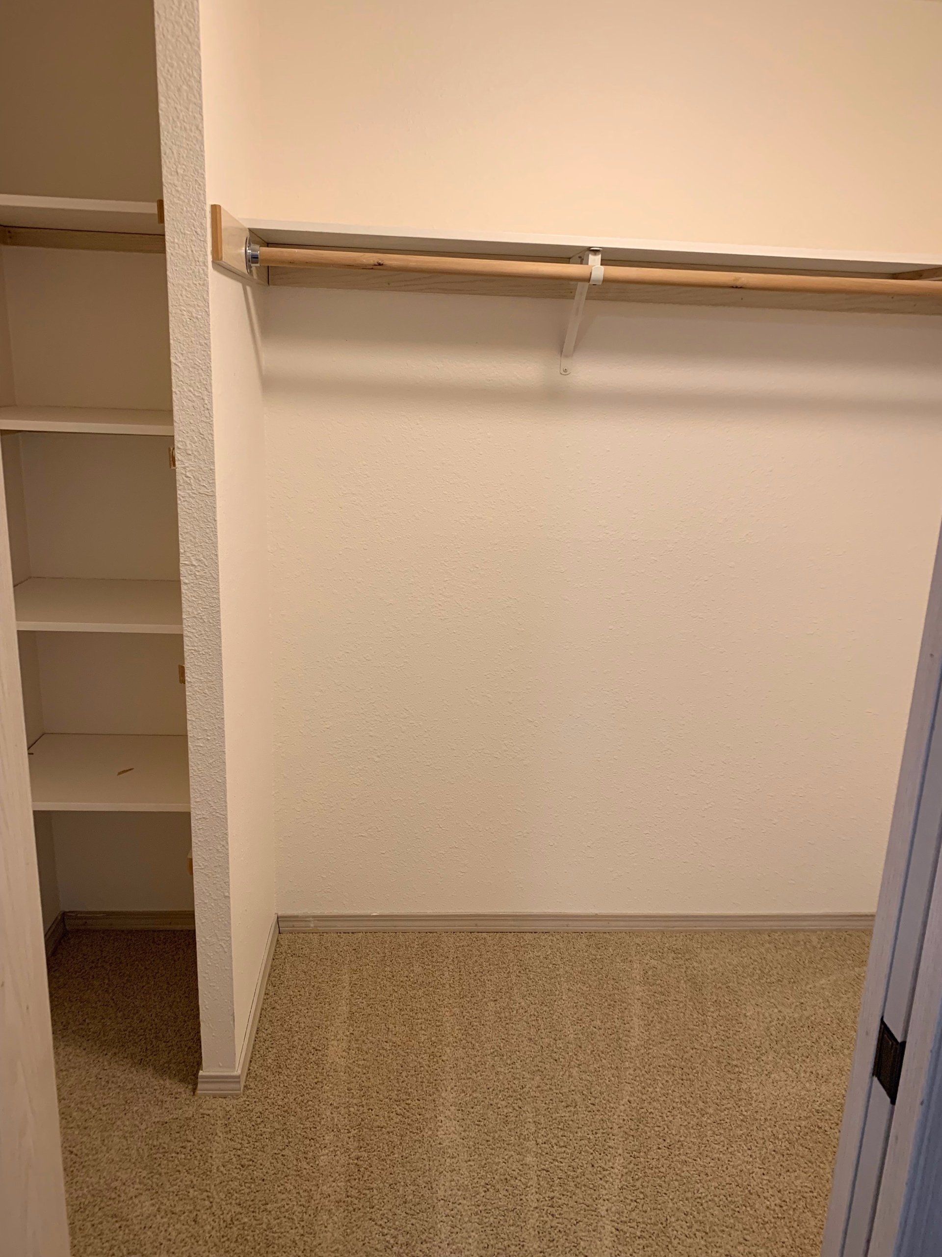 An empty walk in closet with shelves and a hanger.