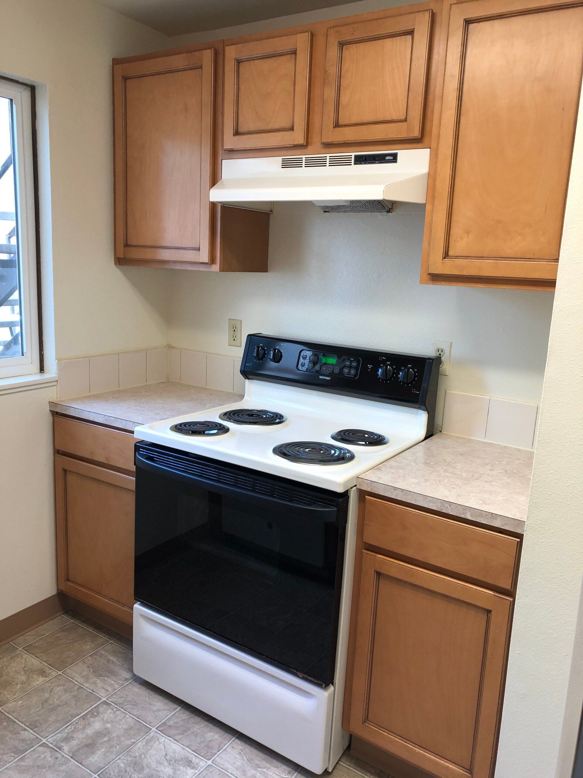 A kitchen with a stove top oven and wooden cabinets