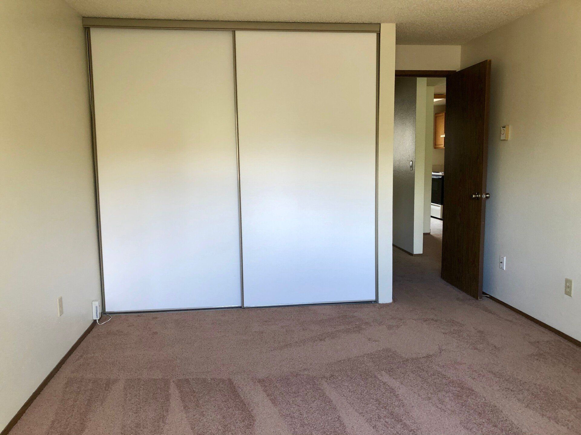 An empty bedroom with sliding glass doors and a carpeted floor.