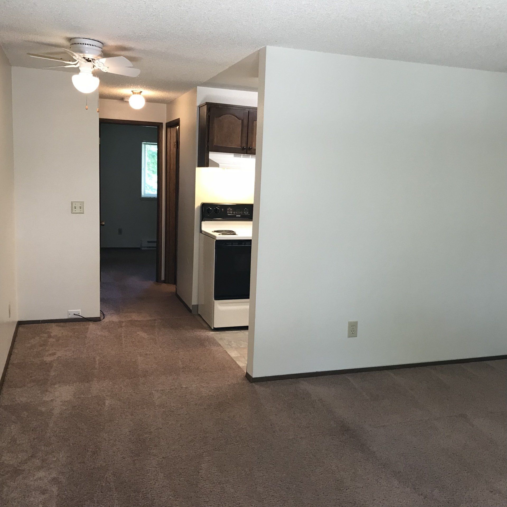 A living room with a ceiling fan and a stove