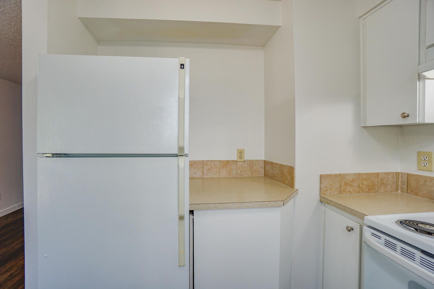 White refrigerator and cabinets in a small, bright kitchen with a countertop and oven.