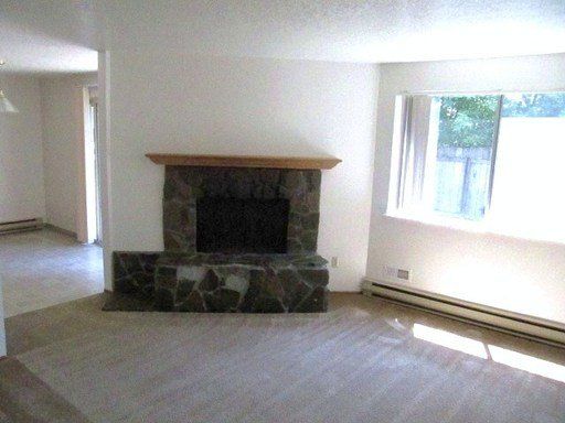 An empty living room with a fireplace and a window