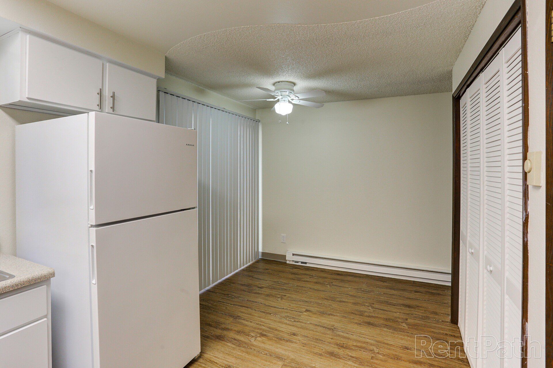A kitchen with a refrigerator and a ceiling fan.