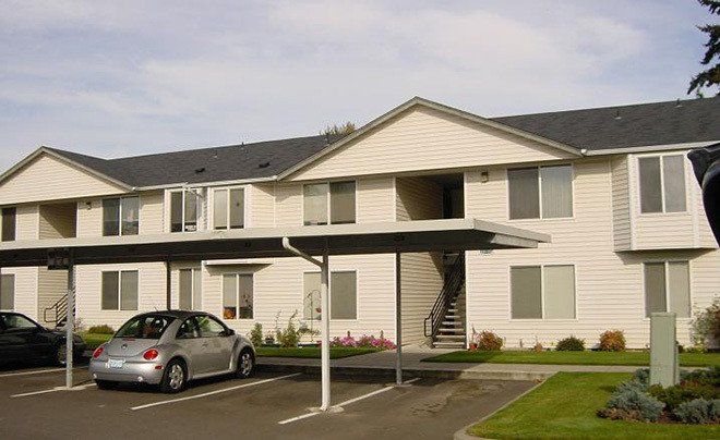 A car is parked under a canopy in front of a building