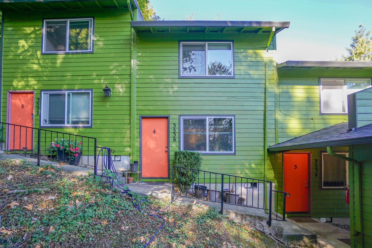 Row of green townhouses with orange doors.