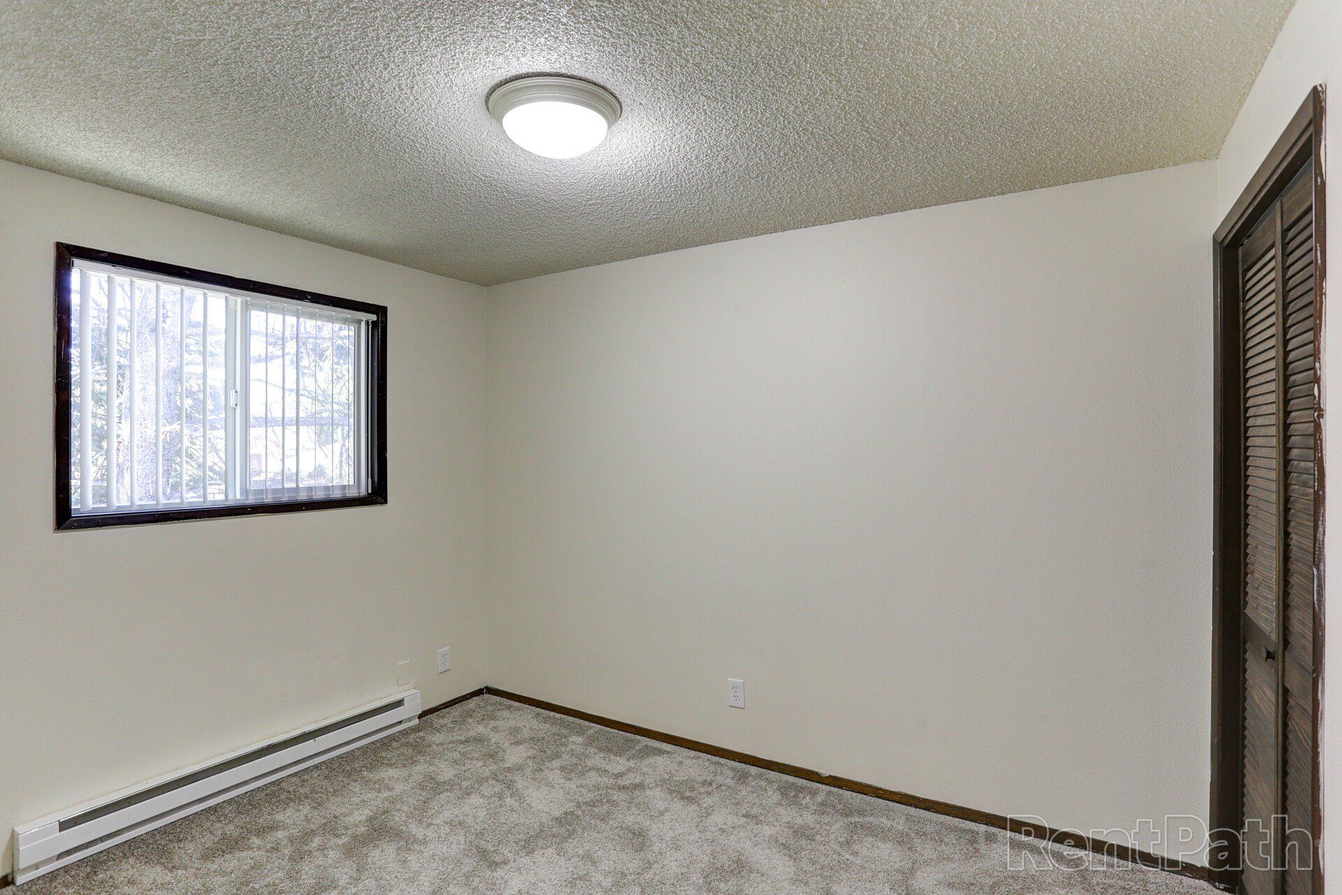 An empty bedroom with a window and a light on the ceiling.
