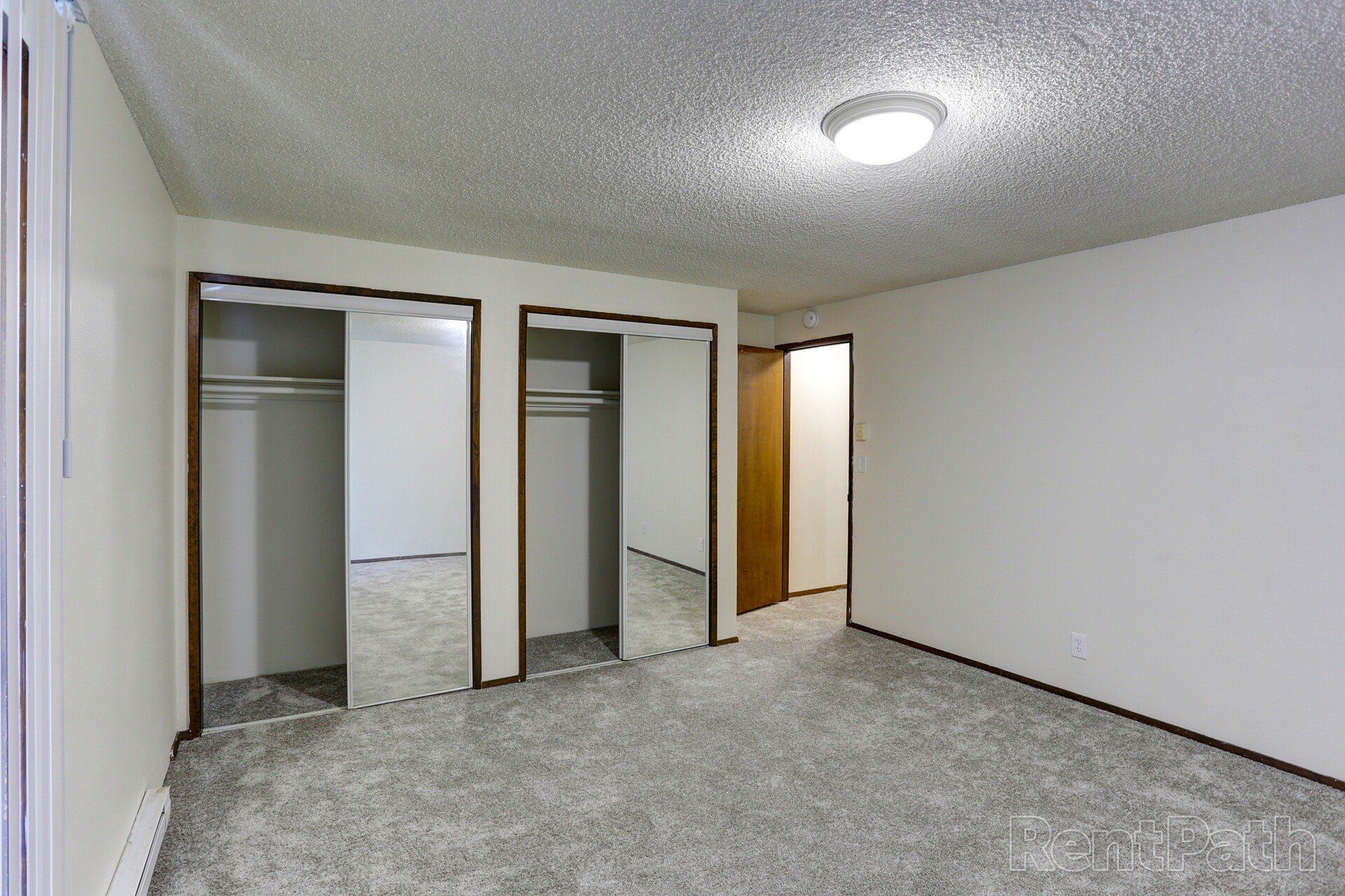 An empty bedroom with two closets and a light on the ceiling.