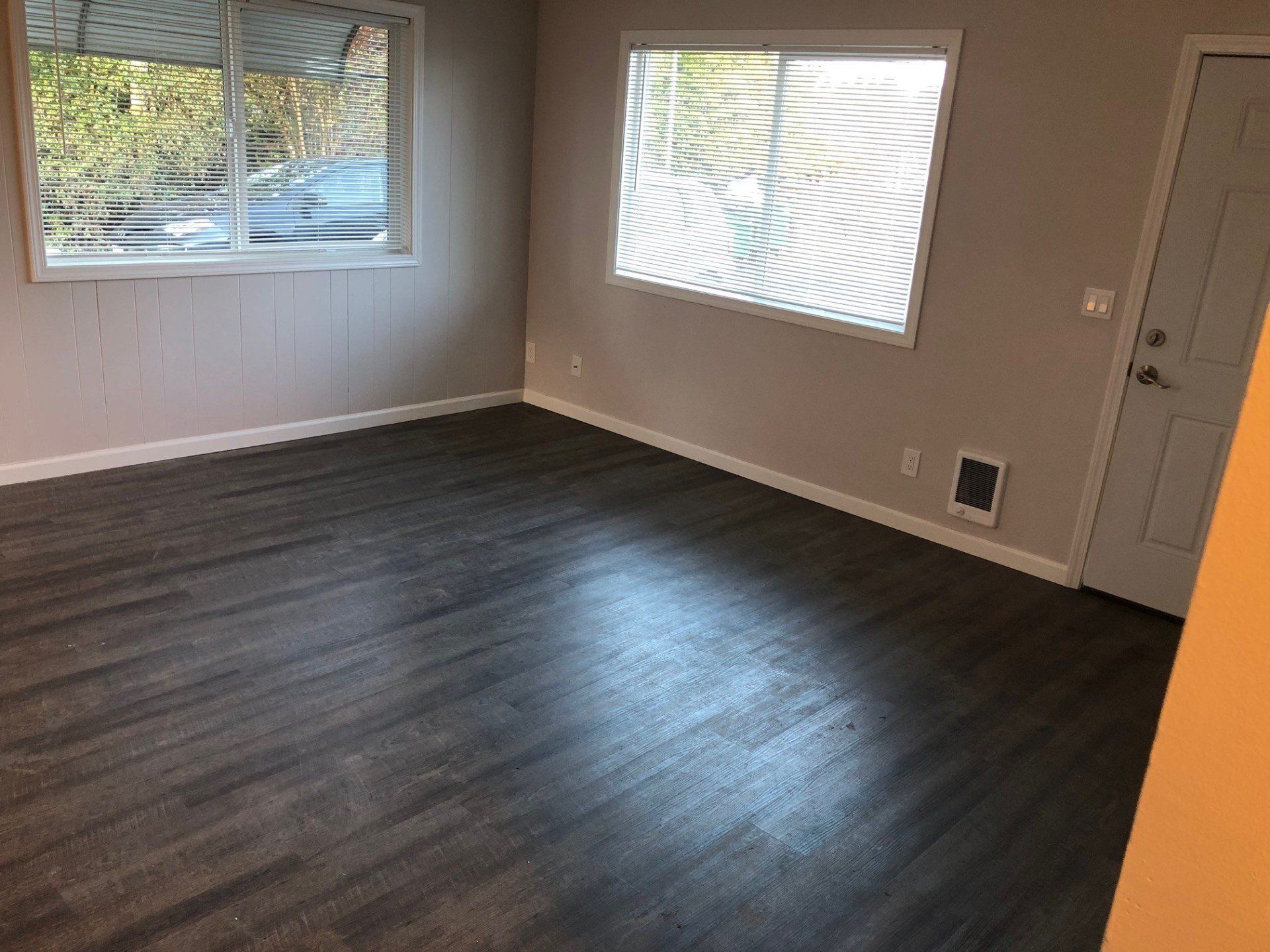 An empty living room with hardwood floors and a window.