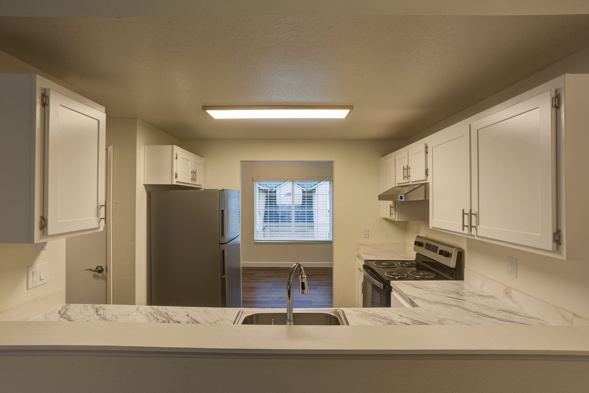 A kitchen with white cabinets , a stove , a refrigerator , and a sink.