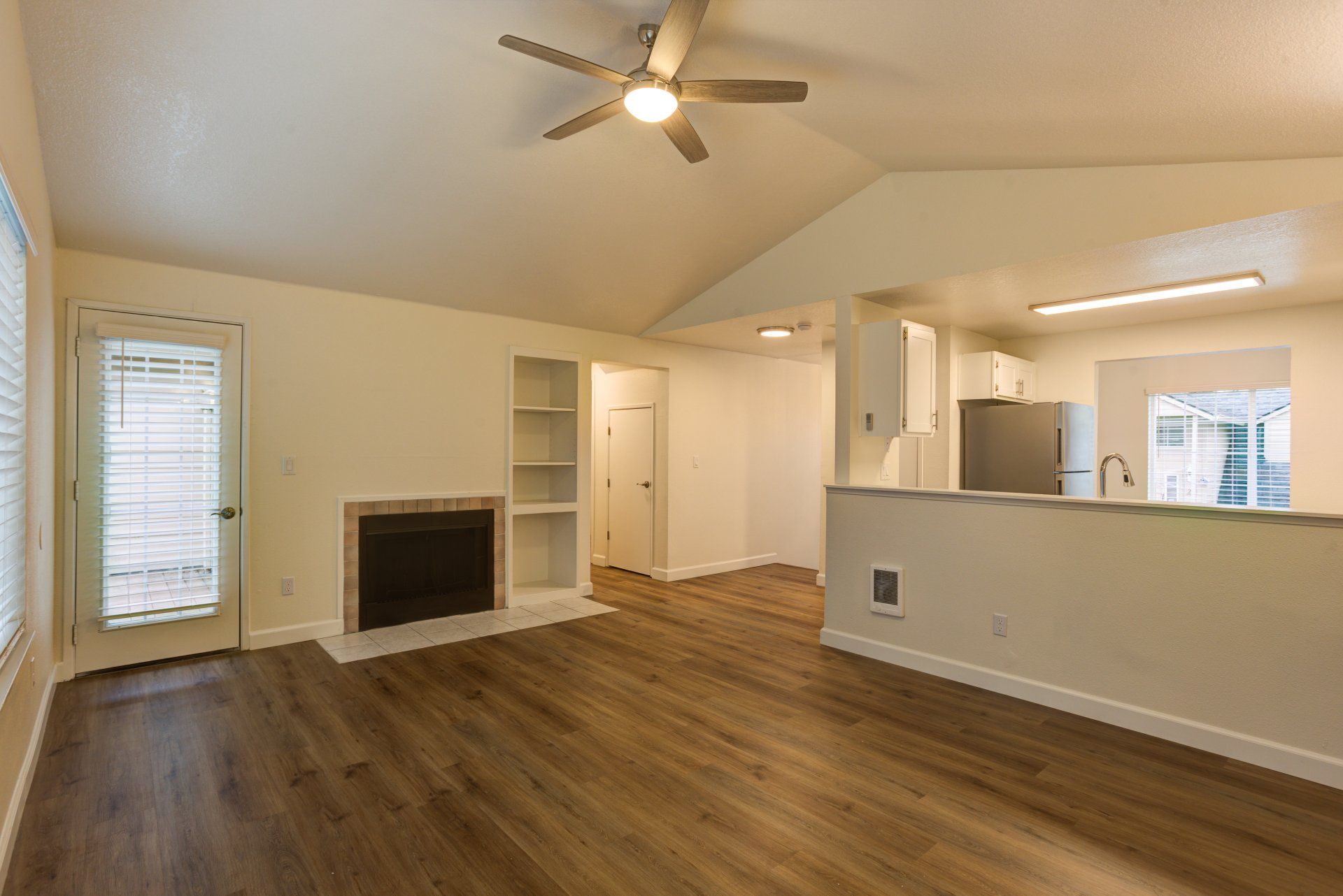 An empty living room with a fireplace and a ceiling fan.
