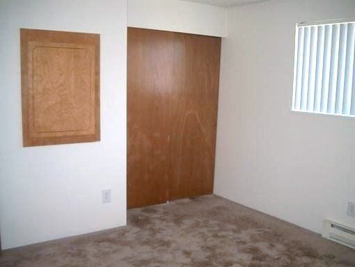 An empty bedroom with a closet and a window.