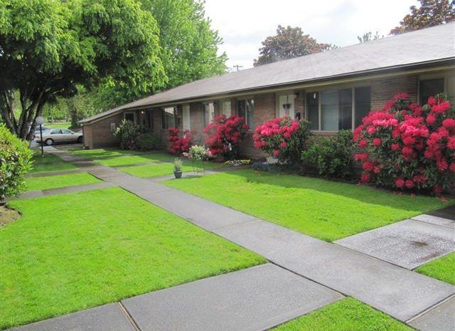 A house with a lush green lawn and flowers in front of it