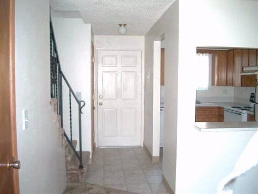 A hallway with stairs leading to a door and a kitchen