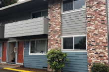 A brick apartment building with blue siding and a balcony