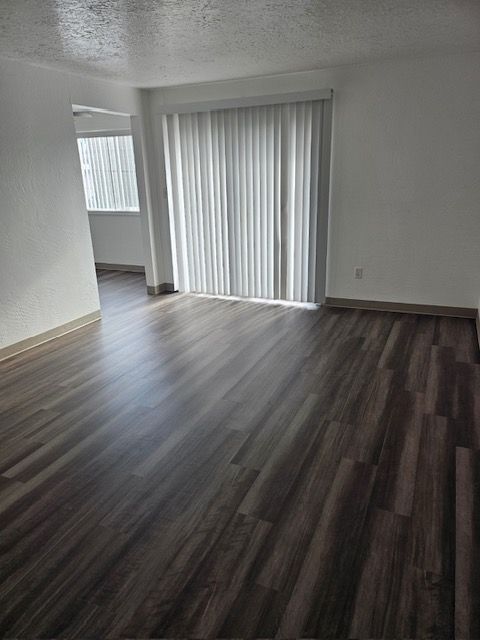 An empty living room with hardwood floors and a sliding glass door.