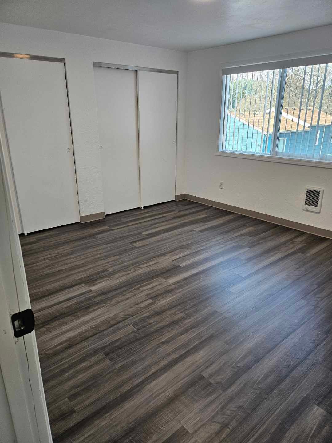 A living room with hardwood floors and a window.