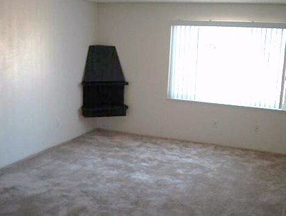 An empty living room with a fireplace and a window.