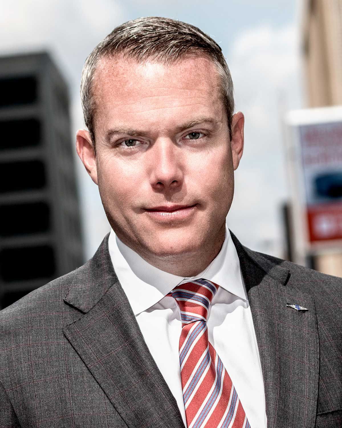 A man in a suit and tie is standing in front of a building.