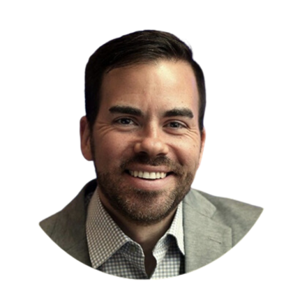 A man in a suit and plaid shirt smiles for the camera