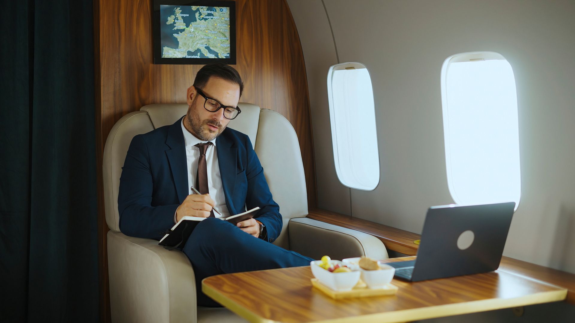 Businessman writing in a notebook on a plane.  