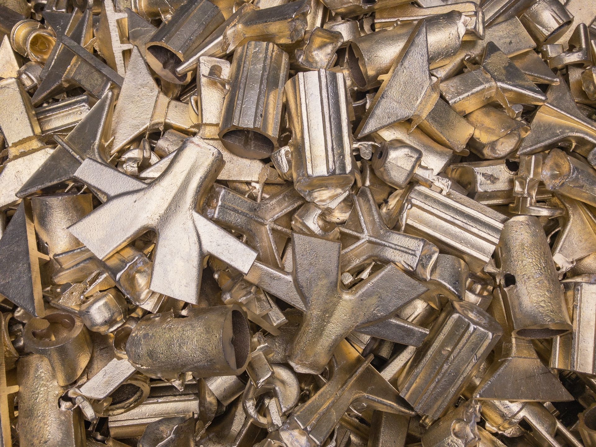 Pile of irregularly shaped, silvery-gold metal objects, possibly scrap or industrial components.