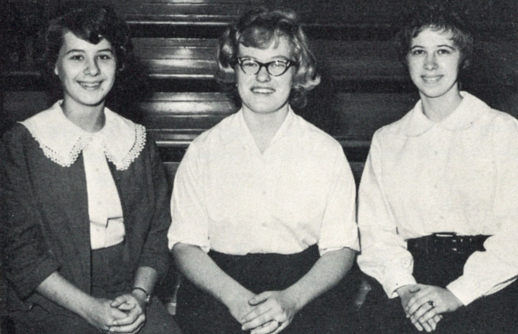 Three seated, smiling female students.