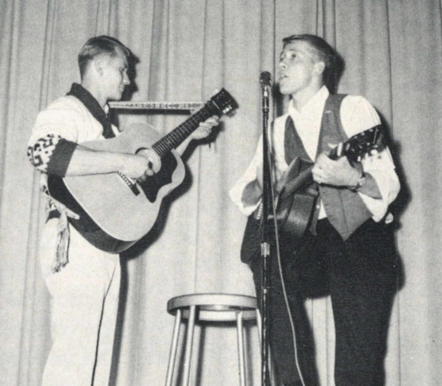 Two male students on stage performing with guitars - one of them is singing
