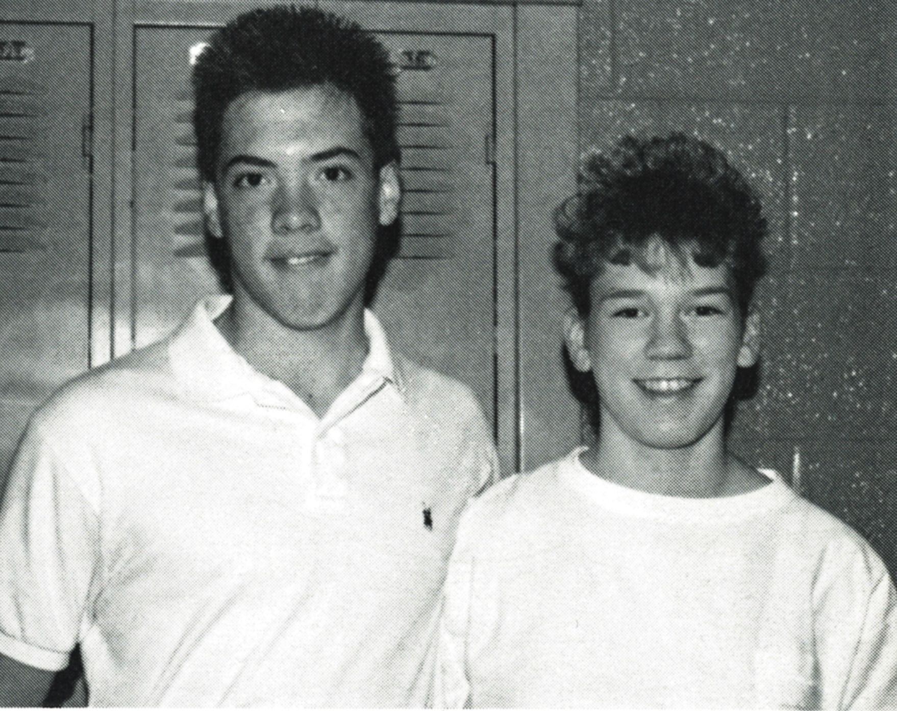 Two smiling students by lockers