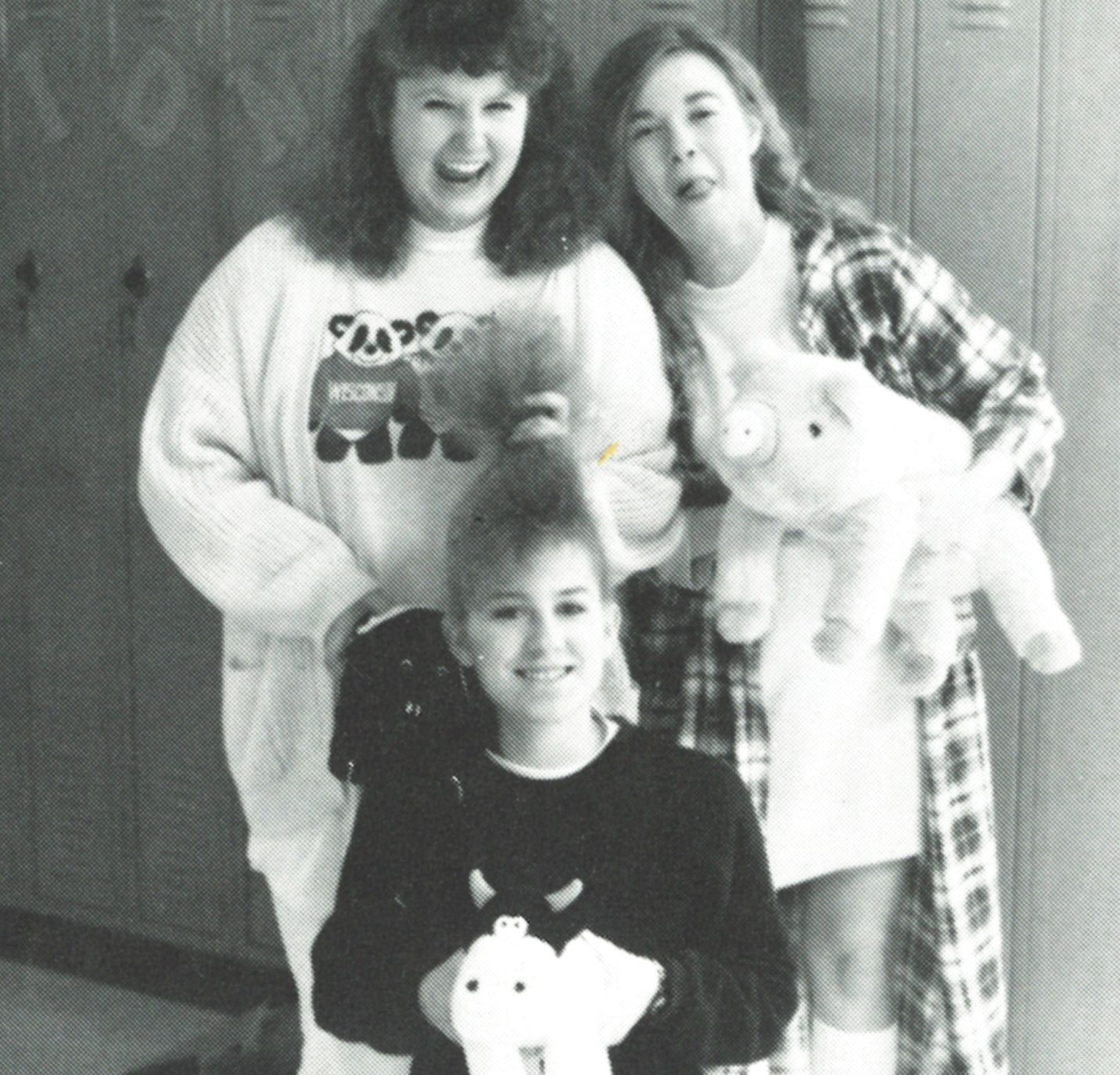 Three girls, two of which are holding stuffed animals